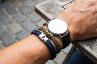 Bracelet cordon homme tressé marine et olive porté au poignet avec une montre minimaliste sur terrasse urbaine
