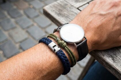 Bracelet cordon homme tressé marine et olive porté au poignet avec une montre minimaliste sur terrasse urbaine